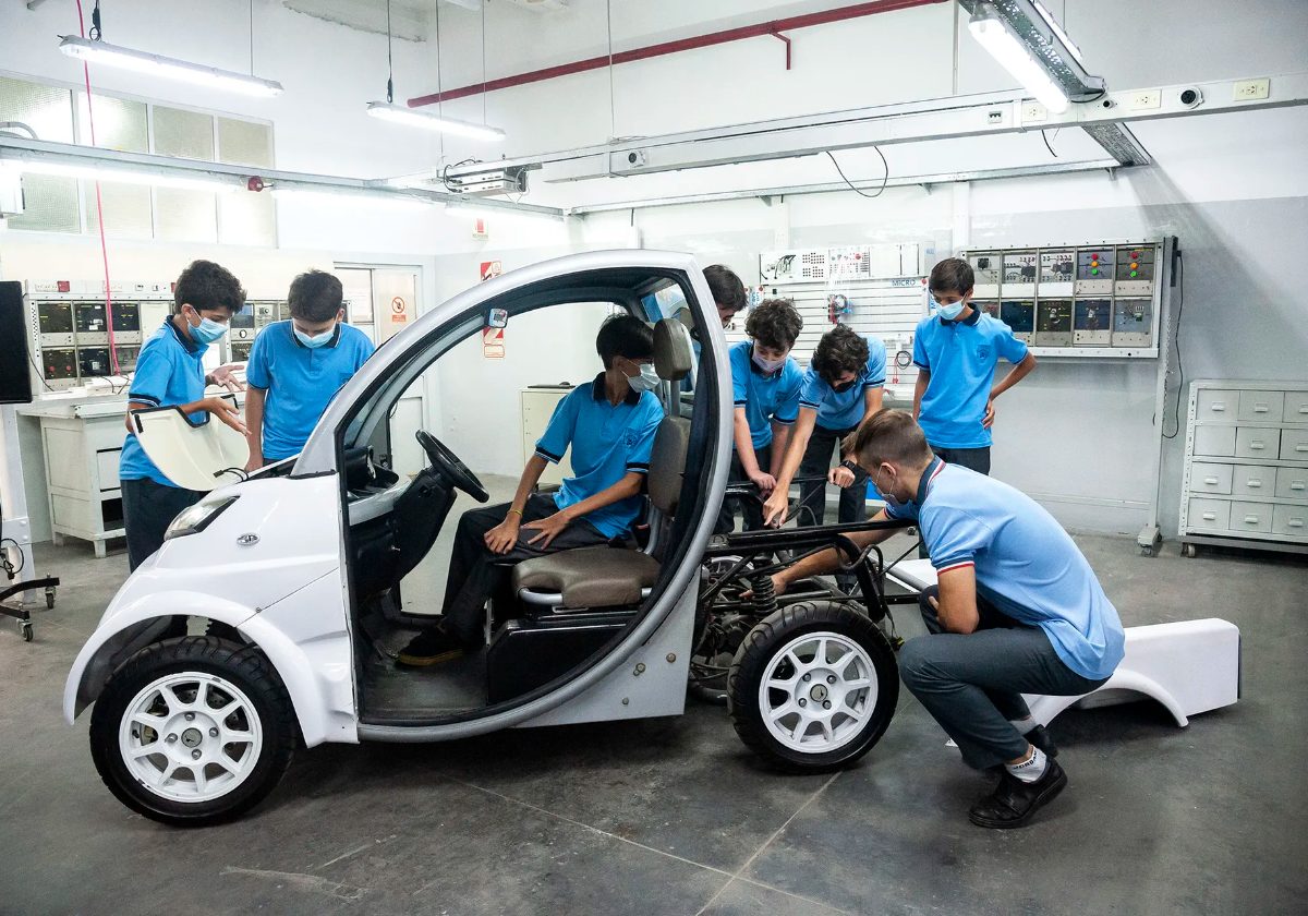 Estudiantes trabajando sobre un vehículo eléctrico en taller escolar